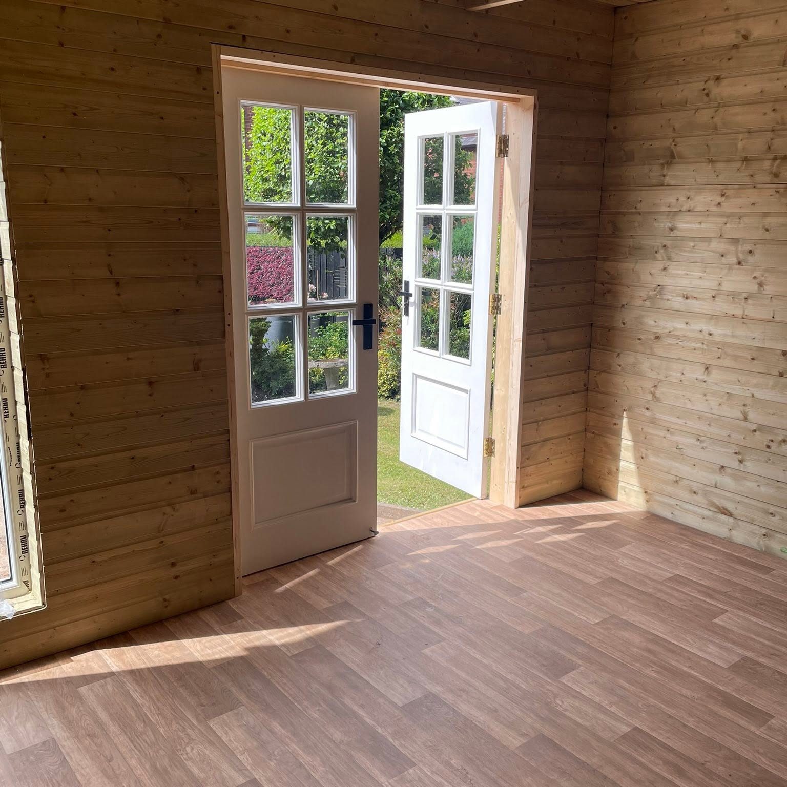 Room with wood walls, floor and double doors leading to garden